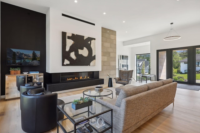 living room featuring recessed lighting, wood finished floors, and a glass covered fireplace