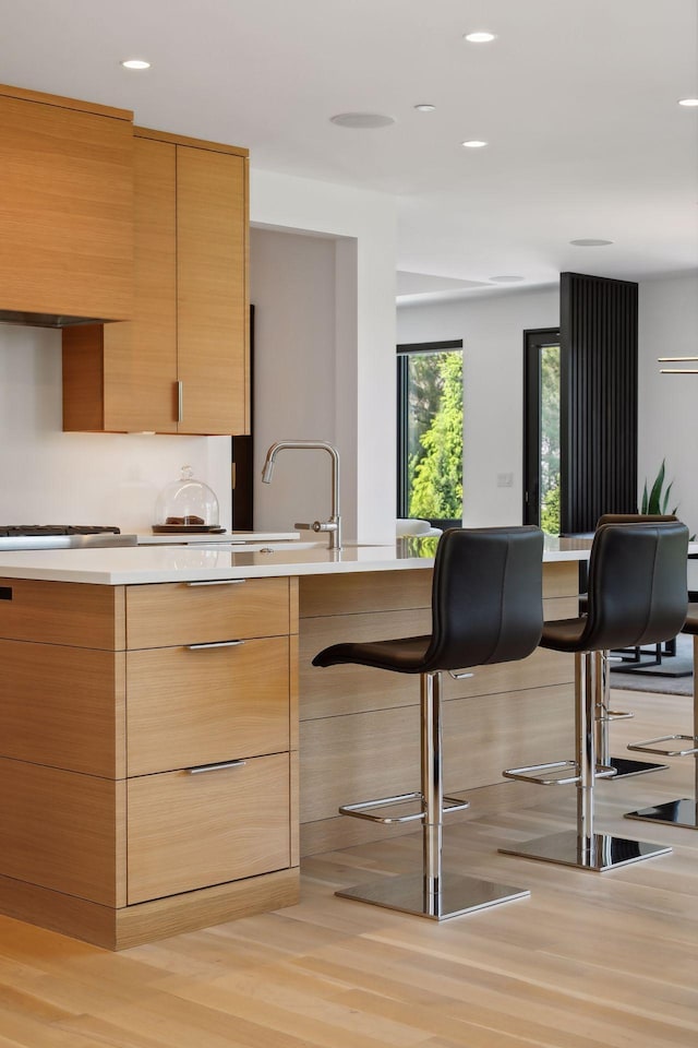 kitchen featuring stainless steel gas cooktop, a breakfast bar area, recessed lighting, light countertops, and modern cabinets