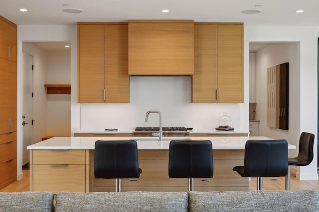 kitchen featuring light countertops, a breakfast bar, modern cabinets, and a center island with sink