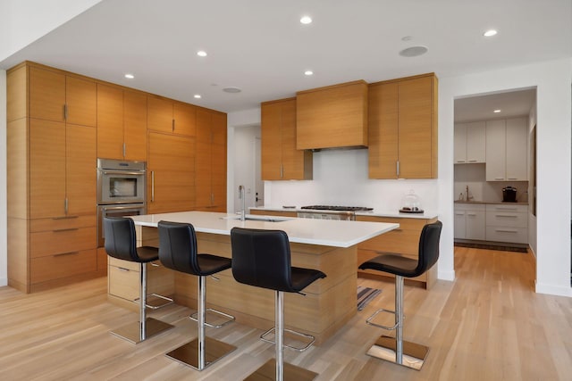 kitchen featuring a breakfast bar, light wood-type flooring, a sink, and gas stovetop