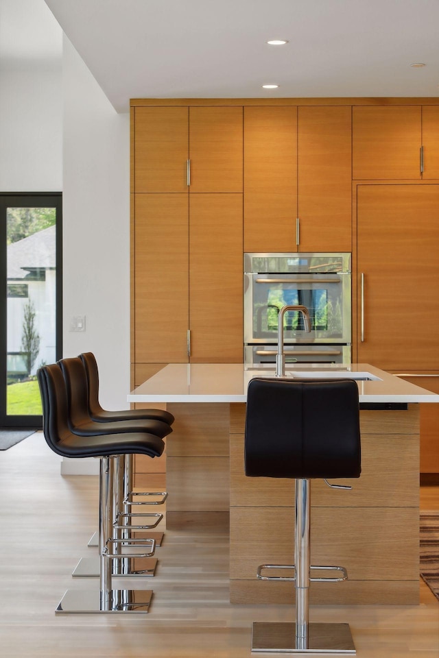 kitchen with double oven, a kitchen bar, and light countertops