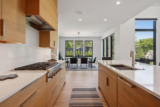 kitchen featuring light countertops, light wood-style floors, stainless steel gas cooktop, a sink, and recessed lighting