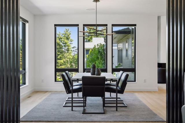 dining area featuring a notable chandelier, baseboards, and wood finished floors