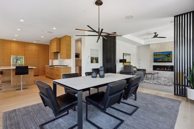 dining room with light wood-type flooring, a fireplace, ceiling fan, and recessed lighting