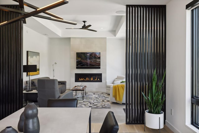 living area featuring ceiling fan, a fireplace, and wood finished floors