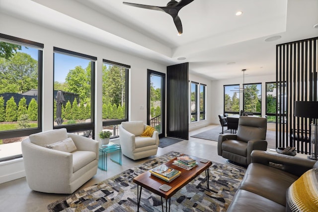 living area with recessed lighting, a raised ceiling, and ceiling fan