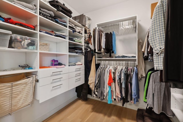 walk in closet with light wood-style floors