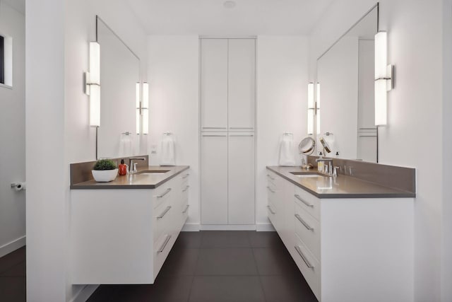 full bathroom with baseboards, two vanities, a sink, and tile patterned floors