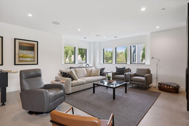 living area with baseboards, concrete floors, and recessed lighting