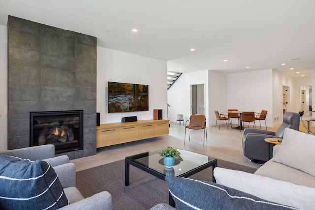 living area featuring recessed lighting, baseboards, a tiled fireplace, and stairs