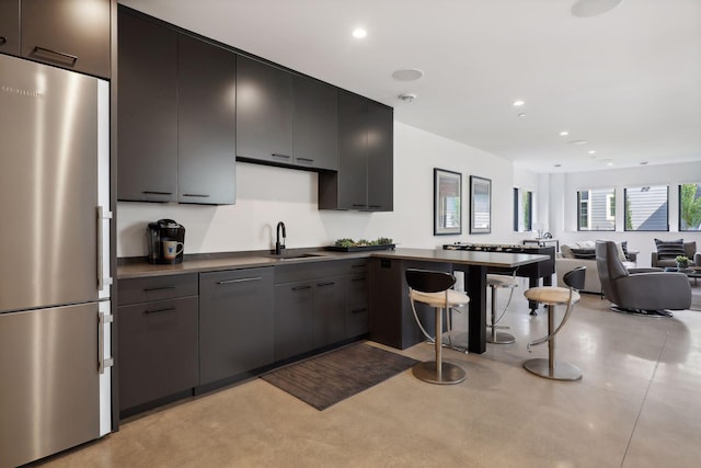 kitchen with finished concrete flooring, open floor plan, freestanding refrigerator, a sink, and recessed lighting