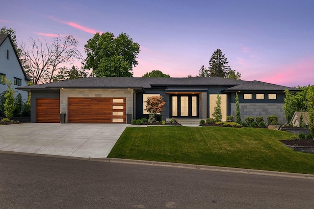 view of front of home featuring an attached garage, concrete driveway, a shingled roof, and a front yard