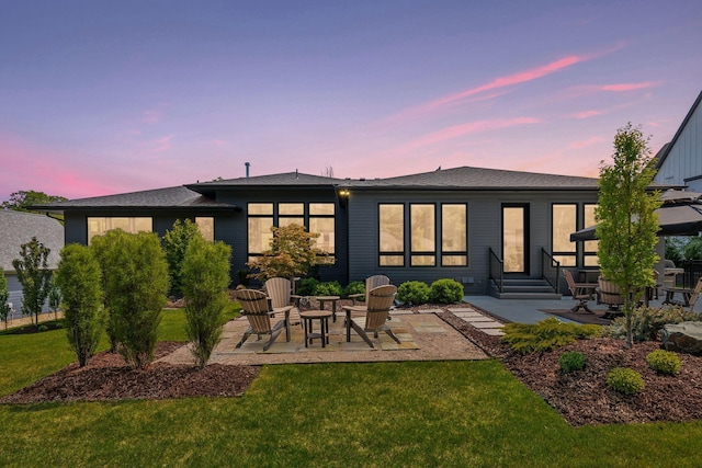 back of property at dusk featuring a patio and a yard