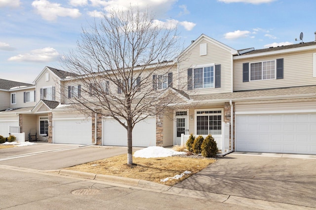 townhome / multi-family property with stone siding and driveway