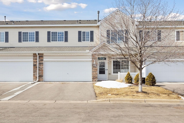 townhome / multi-family property featuring aphalt driveway and stone siding