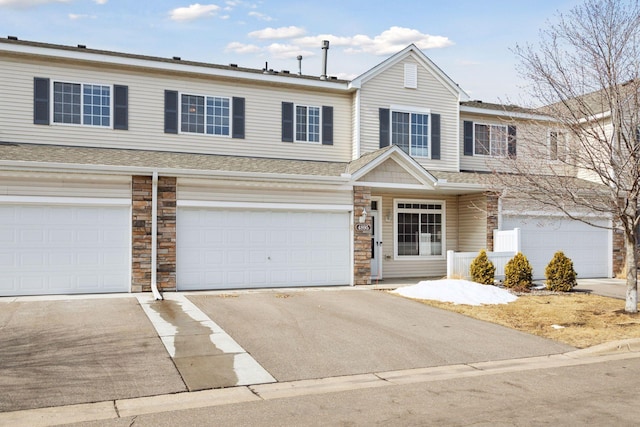 townhome / multi-family property featuring aphalt driveway, an attached garage, stone siding, and roof with shingles