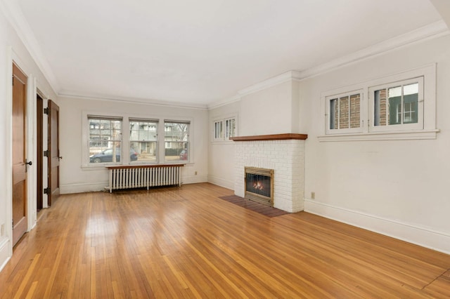 unfurnished living room with light wood-style floors, radiator, crown molding, and a fireplace