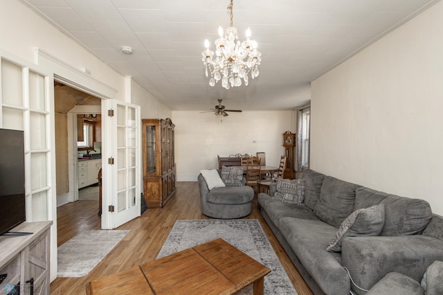 living area featuring ceiling fan with notable chandelier, french doors, and light wood-type flooring