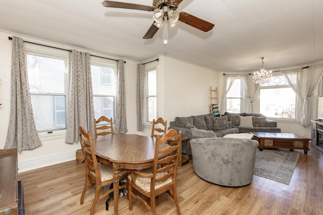 dining room featuring light wood finished floors, ceiling fan with notable chandelier, and baseboards