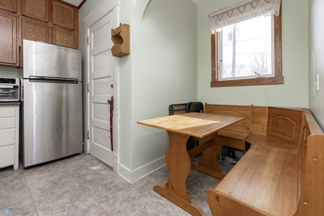 kitchen with brown cabinets, freestanding refrigerator, and baseboards