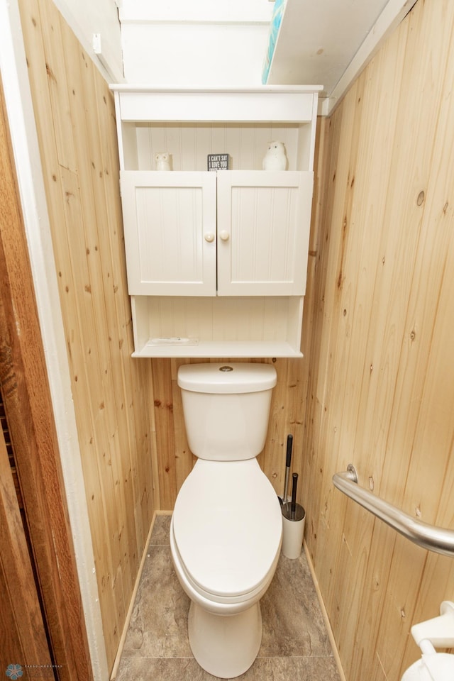 bathroom featuring toilet and wooden walls