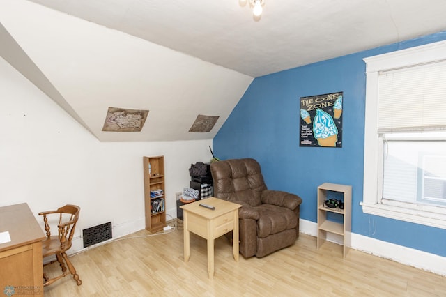 living area featuring lofted ceiling, baseboards, visible vents, and light wood-type flooring