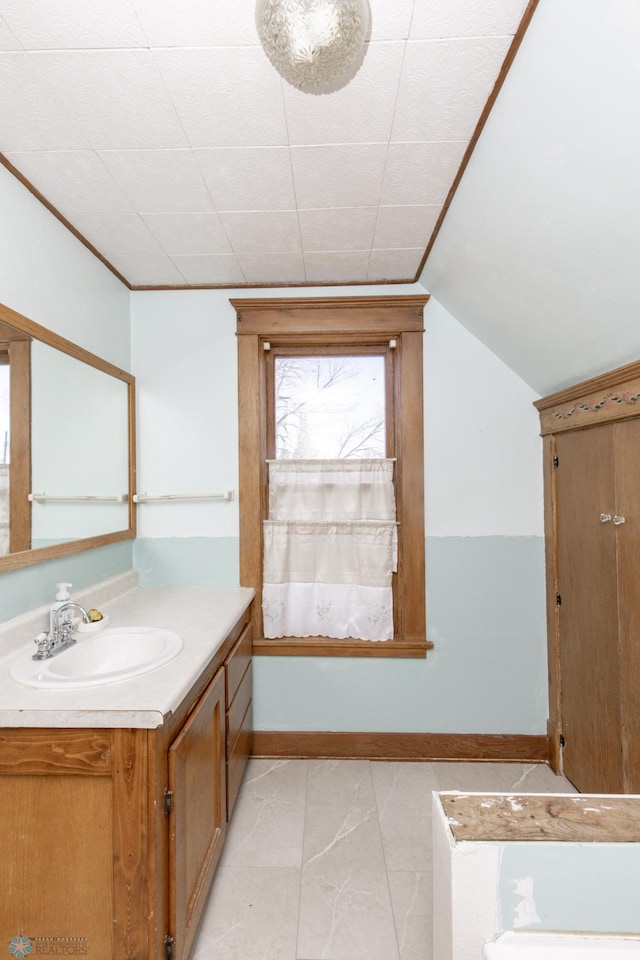 bathroom featuring vanity, baseboards, and vaulted ceiling