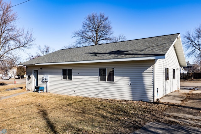 back of house with a yard and a shingled roof