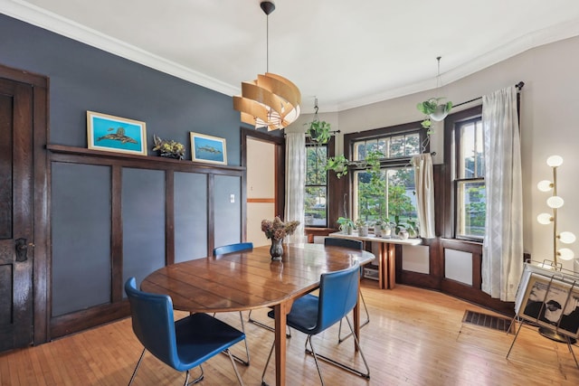 dining area featuring light wood finished floors, visible vents, and crown molding