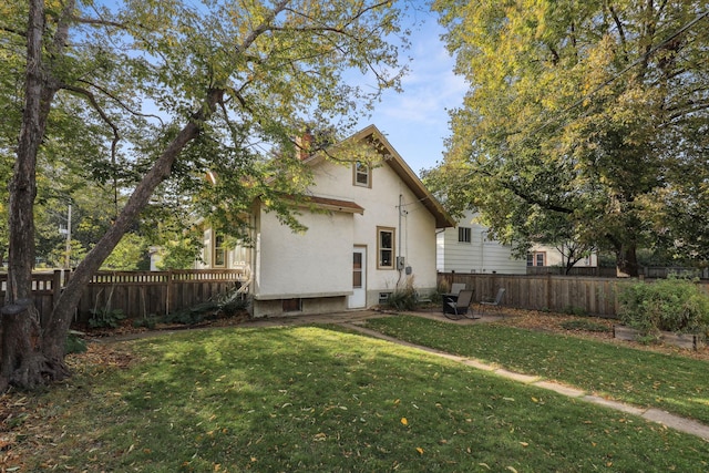 back of house featuring fence private yard, stucco siding, and a yard