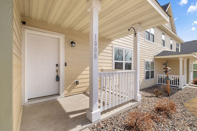 view of exterior entry with a porch and a shingled roof