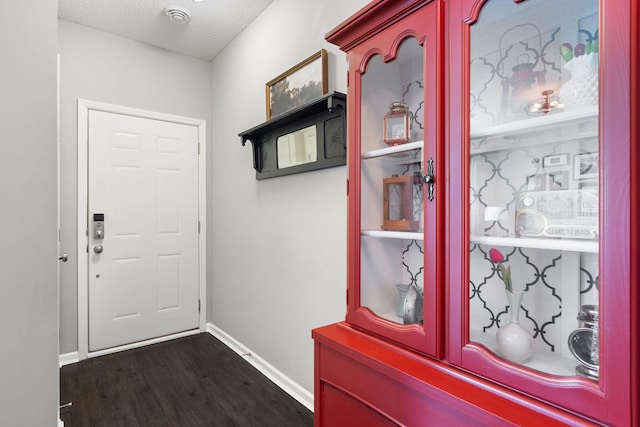 entryway with dark wood-style floors, a textured ceiling, and baseboards