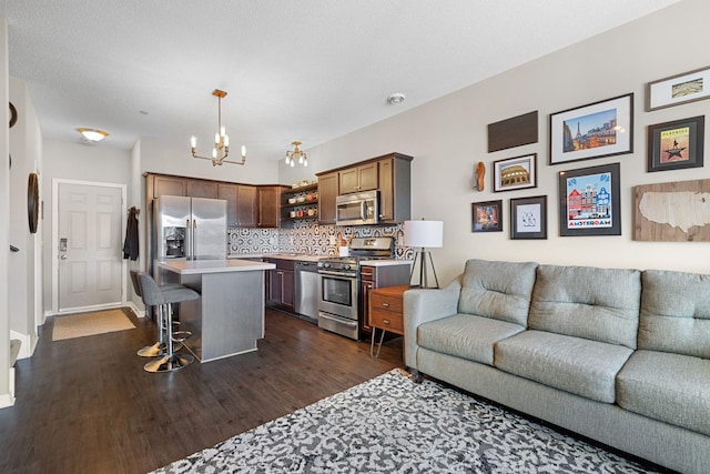 kitchen featuring open floor plan, a kitchen bar, light countertops, stainless steel appliances, and open shelves