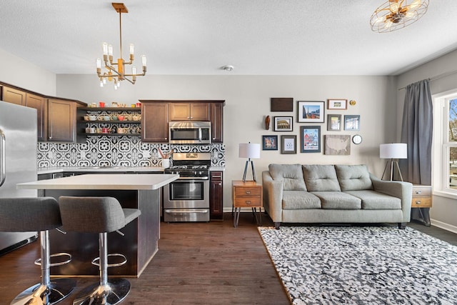 kitchen featuring open shelves, dark wood finished floors, appliances with stainless steel finishes, light countertops, and a chandelier