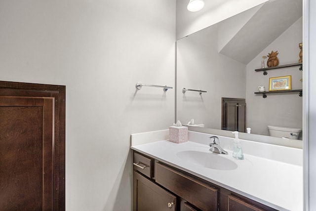 bathroom with toilet, vanity, and vaulted ceiling