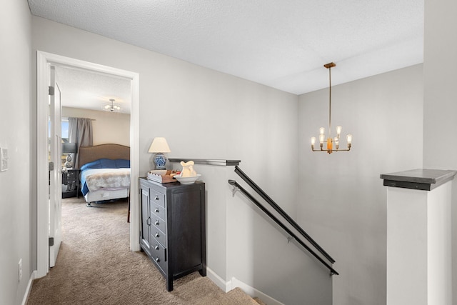 hallway with an upstairs landing, a textured ceiling, light carpet, and baseboards