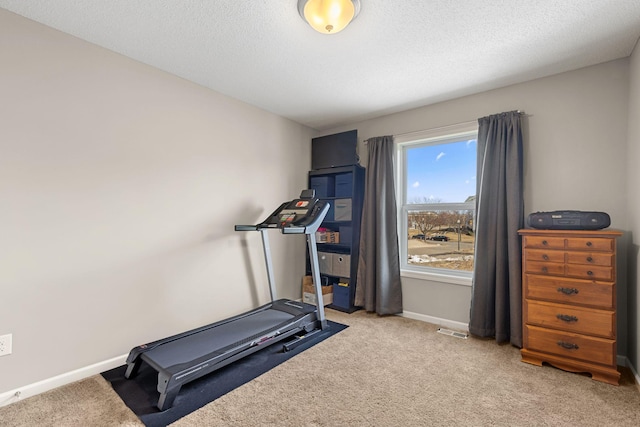 exercise area featuring visible vents, baseboards, carpet, and a textured ceiling