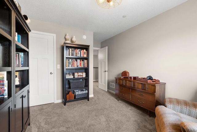 living area featuring carpet flooring, a textured ceiling, baseboards, and visible vents