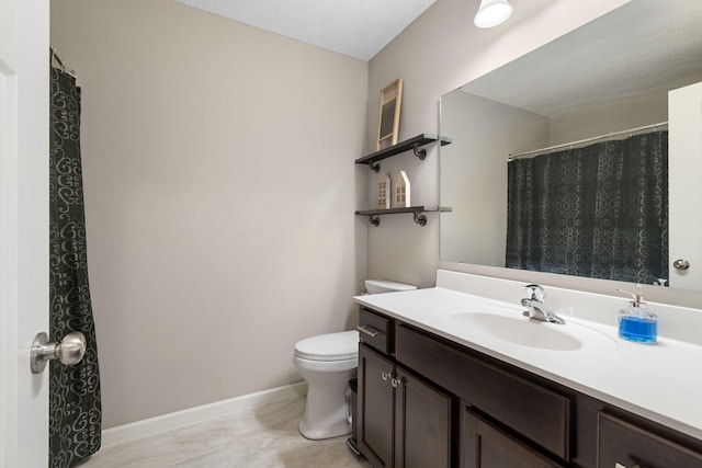 bathroom with toilet, vanity, and baseboards