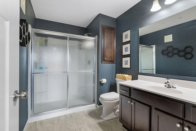 bathroom featuring vanity, a shower stall, and toilet