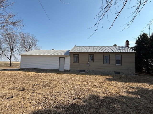 rear view of property featuring metal roof and a chimney