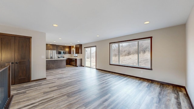 unfurnished living room with light wood-style floors, baseboards, and recessed lighting