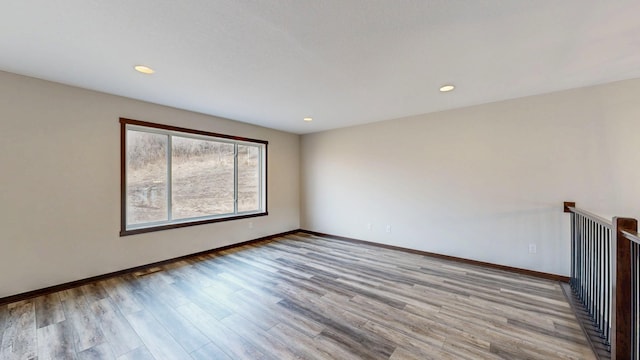 spare room with recessed lighting, baseboards, and wood finished floors