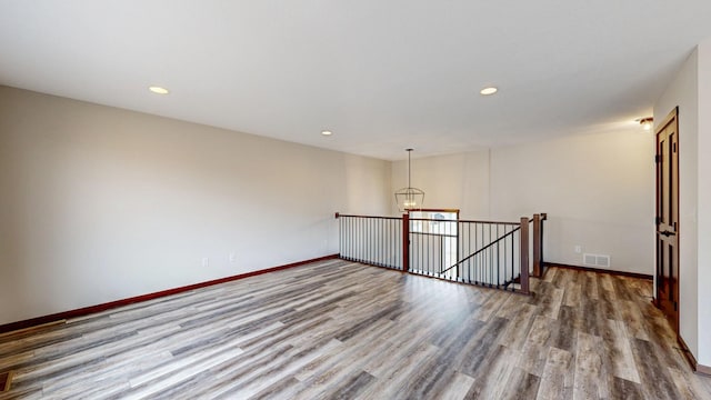 unfurnished room featuring recessed lighting, wood finished floors, visible vents, and baseboards