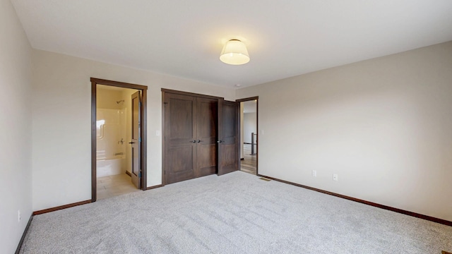 unfurnished bedroom with light carpet, ensuite bath, and baseboards