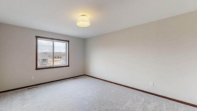 carpeted empty room featuring visible vents and baseboards