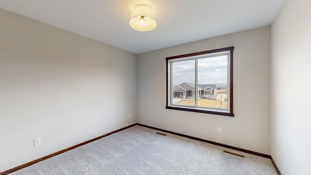 unfurnished room with carpet floors, visible vents, and baseboards