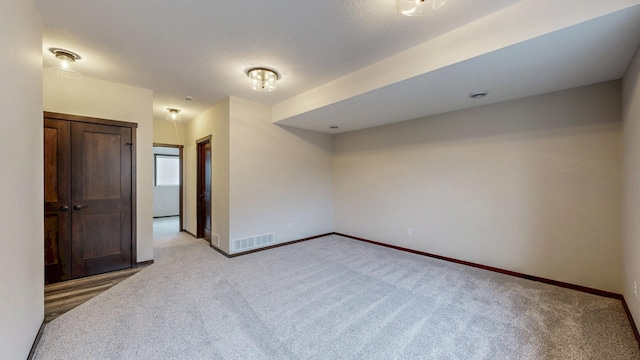 empty room featuring visible vents, light carpet, baseboards, and a textured ceiling