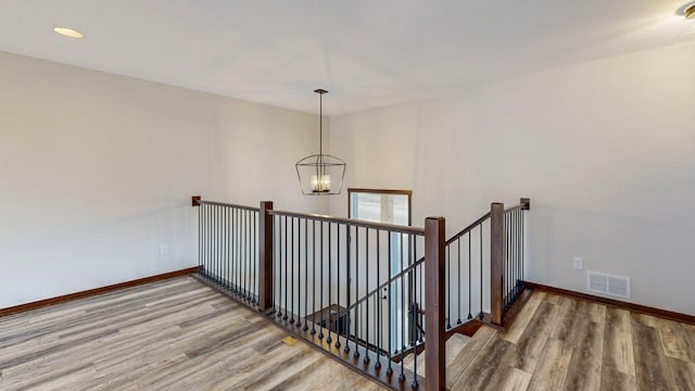 staircase featuring baseboards, visible vents, wood finished floors, an inviting chandelier, and recessed lighting