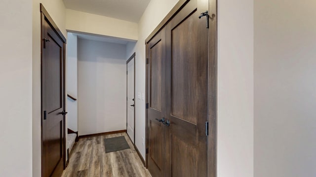 corridor featuring light wood-type flooring and baseboards